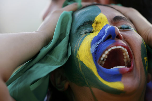 A fan of Brazil reacts while watching a broadcast of the 2014 World Cup semi-final against Germany at the Fan Fest in Brasilia